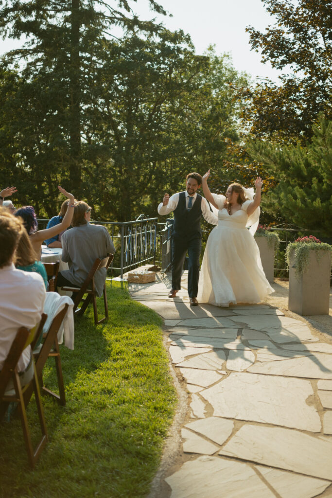 Bride and groom making their grand entrance into the wedding reception, greeted by cheering guests.