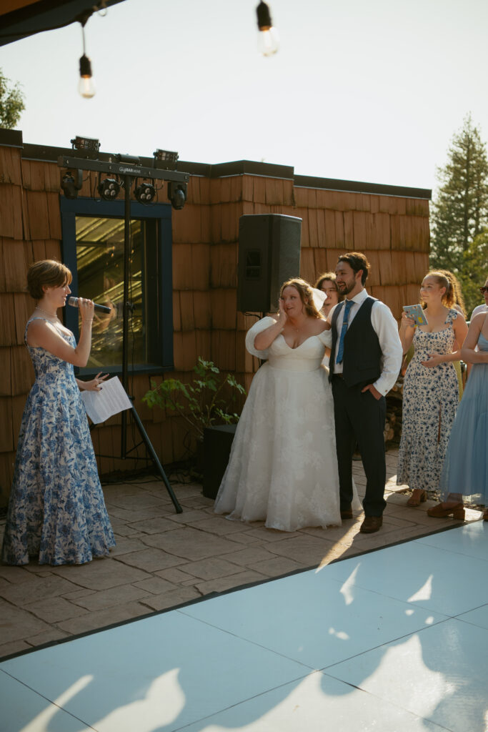 Guests laughing and crying during emotional wedding toasts, captured during reception coverage by hybrid photo and video team.