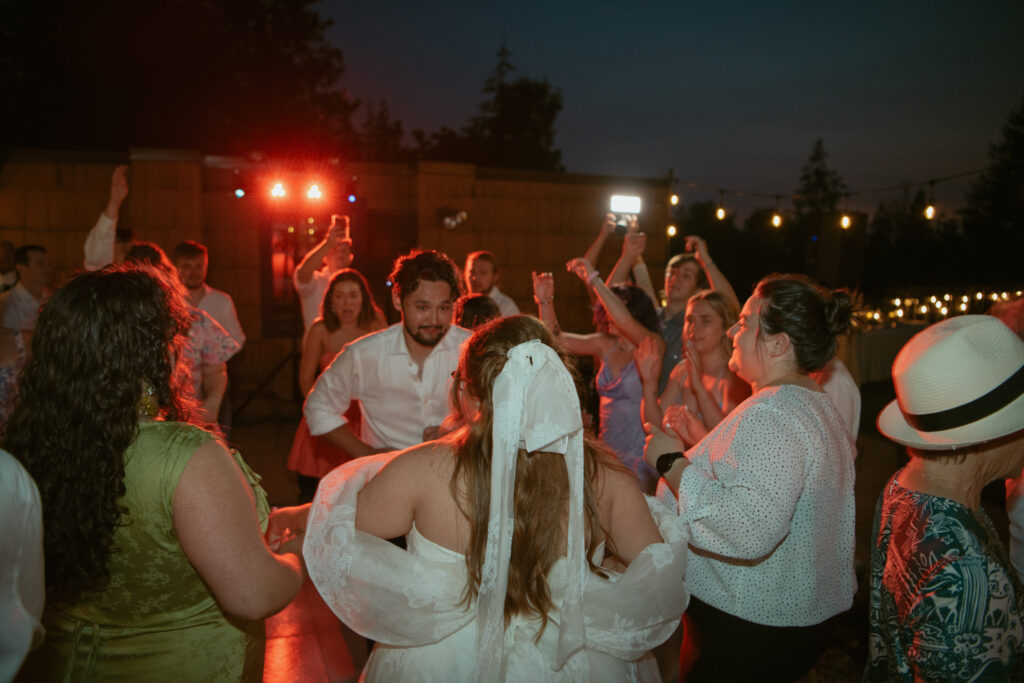 A vibrant photo of wedding guests dancing and celebrating during the reception. Captured by an Oregon-based destination wedding photographer and videographer specializing in hybrid wedding coverage that captures both the big moments and the fun, candid ones.