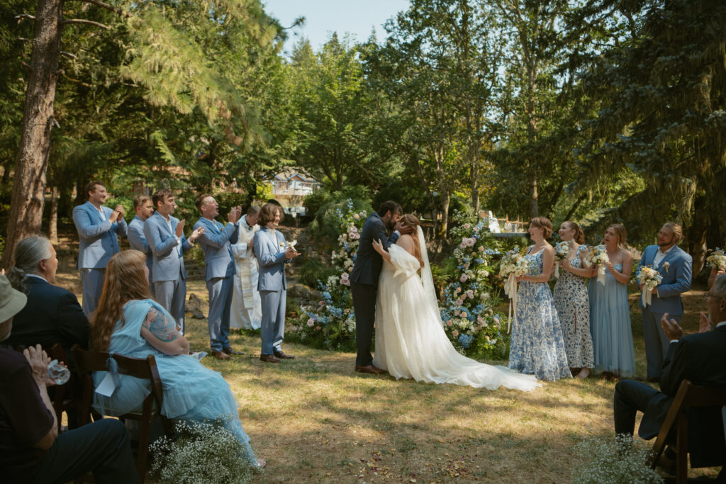 Bride and groom sharing their first kiss as a married couple, captured in a joyful moment during the ceremony.