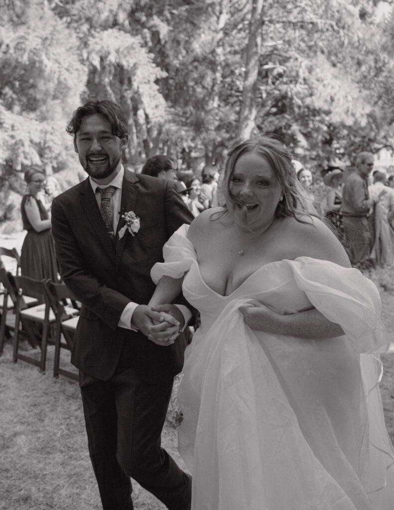 Bride and groom walking hand-in-hand back down the aisle, smiling and celebrating just after their wedding ceremony.