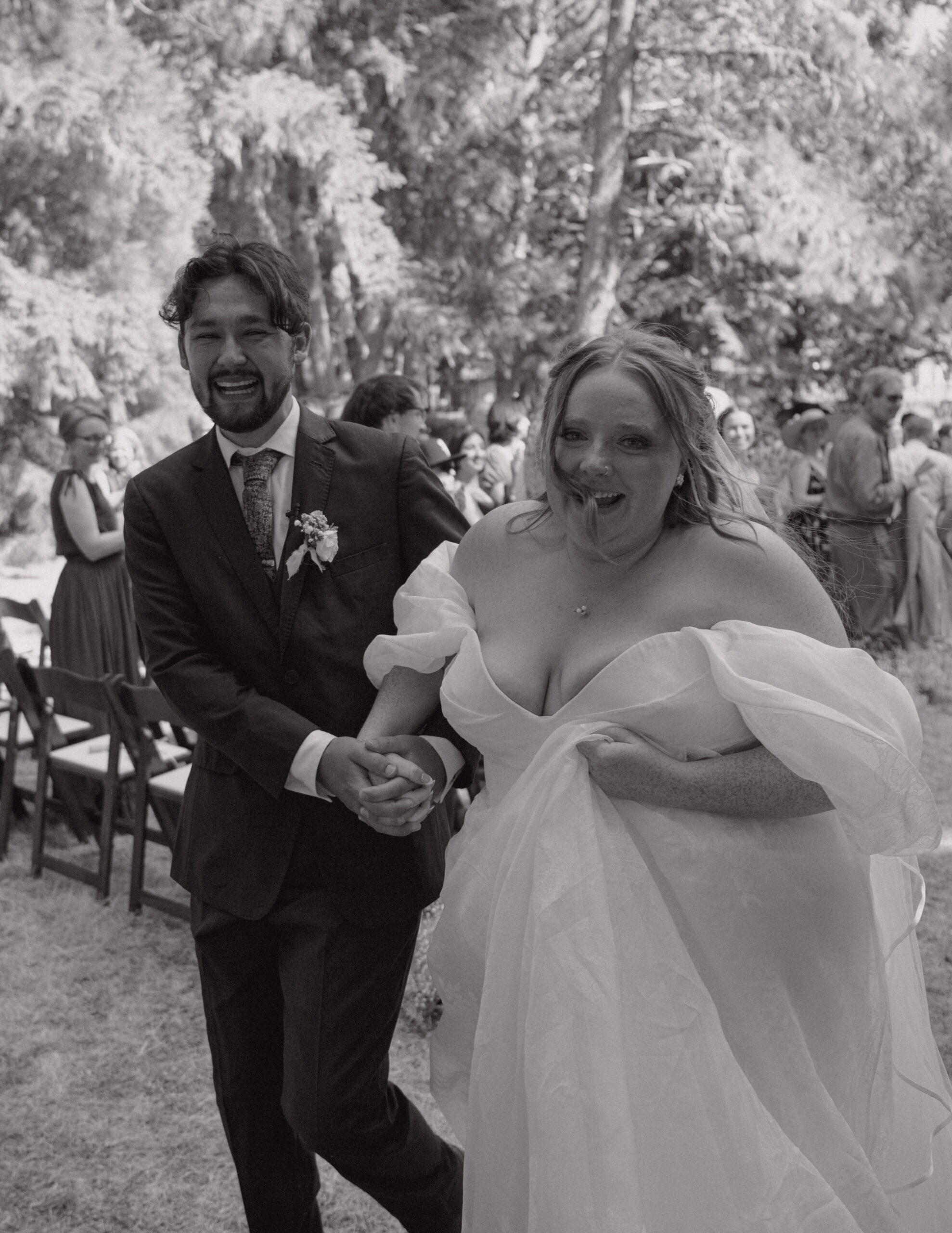 couple walking down the aisle with emotional reactions from guests and excitement , taken by Oregon-based wedding photographer and videographer.
