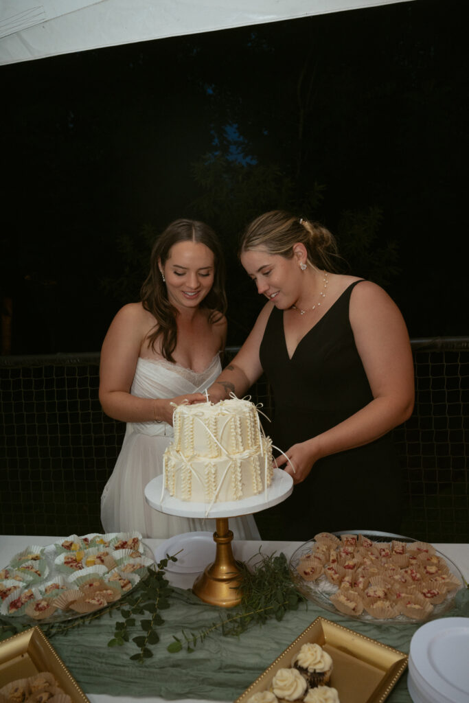 couple cutting a white cake together under the night sky at their oregon backyard wedding 