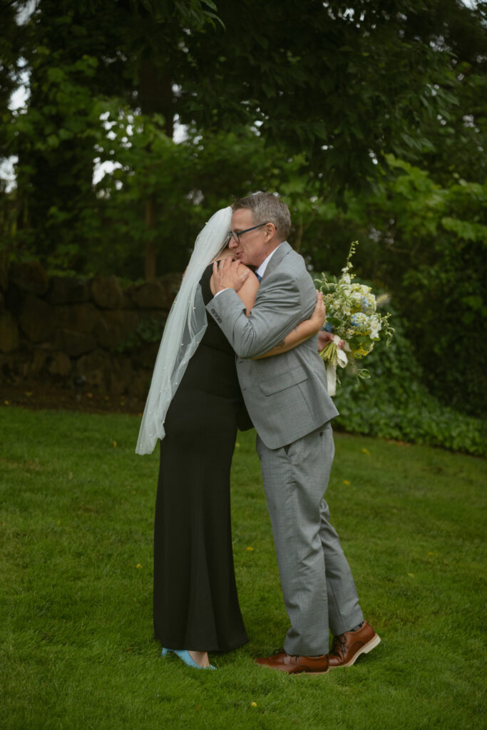 Bride emotional first look with dad at the outdoor backyard wedding venue with friends before the ceremony.
