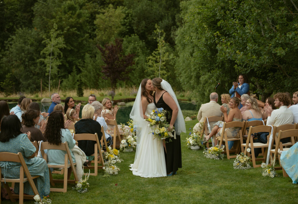 Couple’s first kiss at a rainy Pacific Northwest backyard wedding ceremony in Oregon.